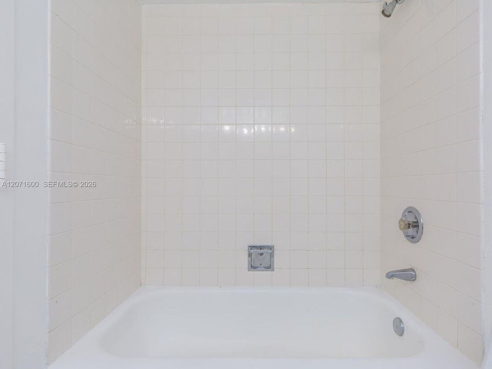 Clean and bright full bath featuring a traditional tub and shower combination with classic tilework.