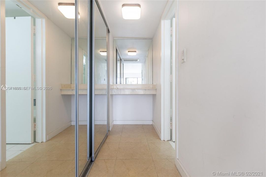 Primary suite hallway offering wall-to-wall mirrored closets and seamless flow into the private bath.