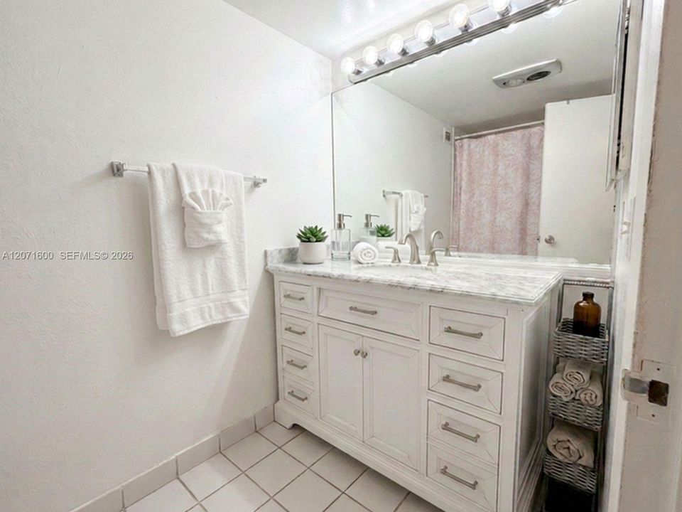 Primary en-suite bathroom featuring an expansive vanity with marble-look counter and ample storage.