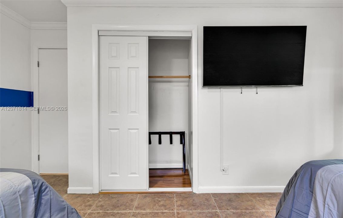 Guest room featuring built-in closet with mounted TV