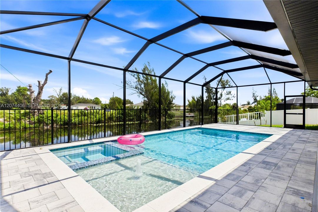 Step outside to SCREENED LANAI w/ HEATED POOL & SPA, landscape, SEAWALL & FULLY EQUIPED OUTDOOR KITCHEN