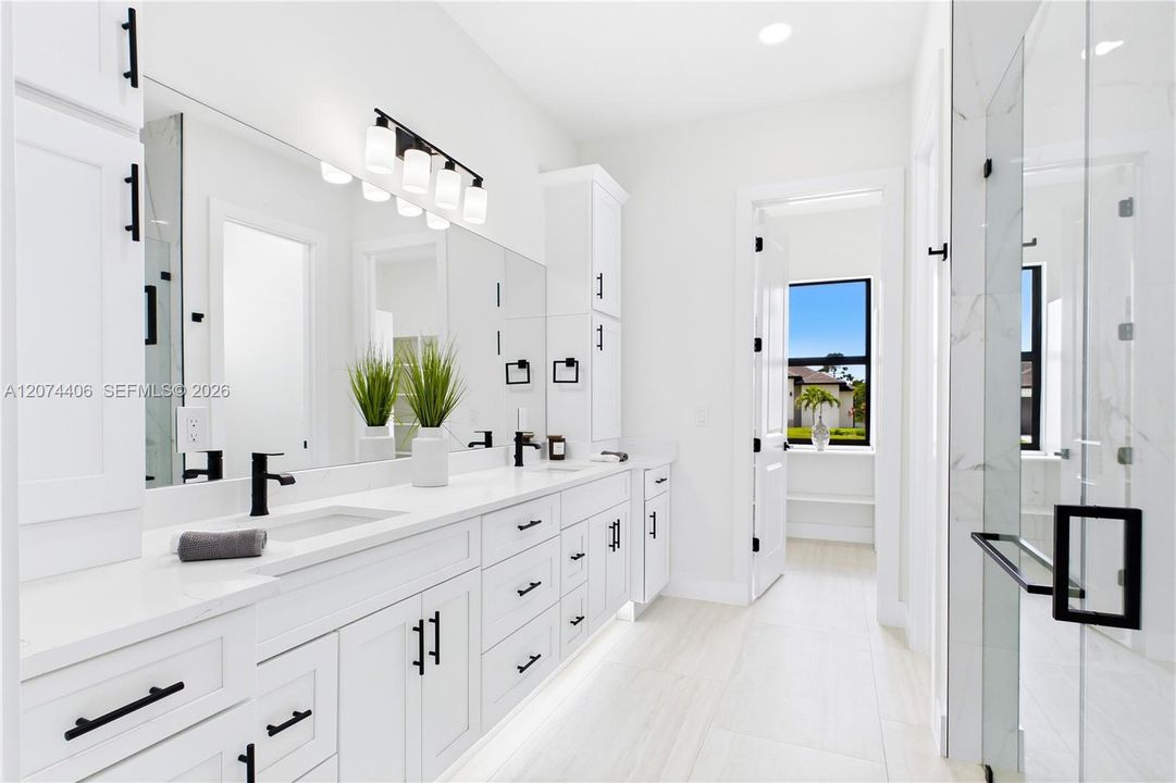 Dual sink vanity w/ quartz countertops, sleek white cabinetry & contemporary lighting complements the spa-like design