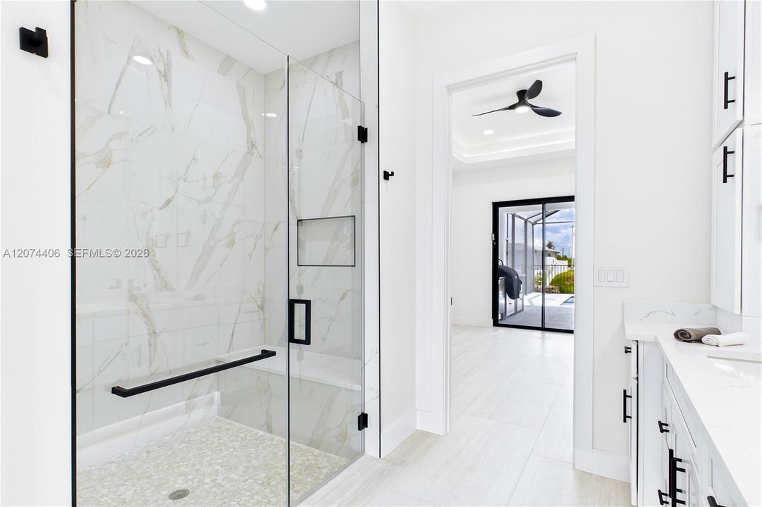 LUXURIOUS PRIMARY BATHROOM w/ spacious WALK-IN GLASS SHOWER w/ floor-to-ceiling designer tile, rainfall showerhead, built-in bench & modern matte-black fixtures