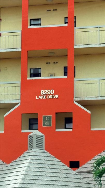 Stucco multi-story exterior featuring tiered balconies, a pyramid-style roof with composite shingles, and prominent building identification signage