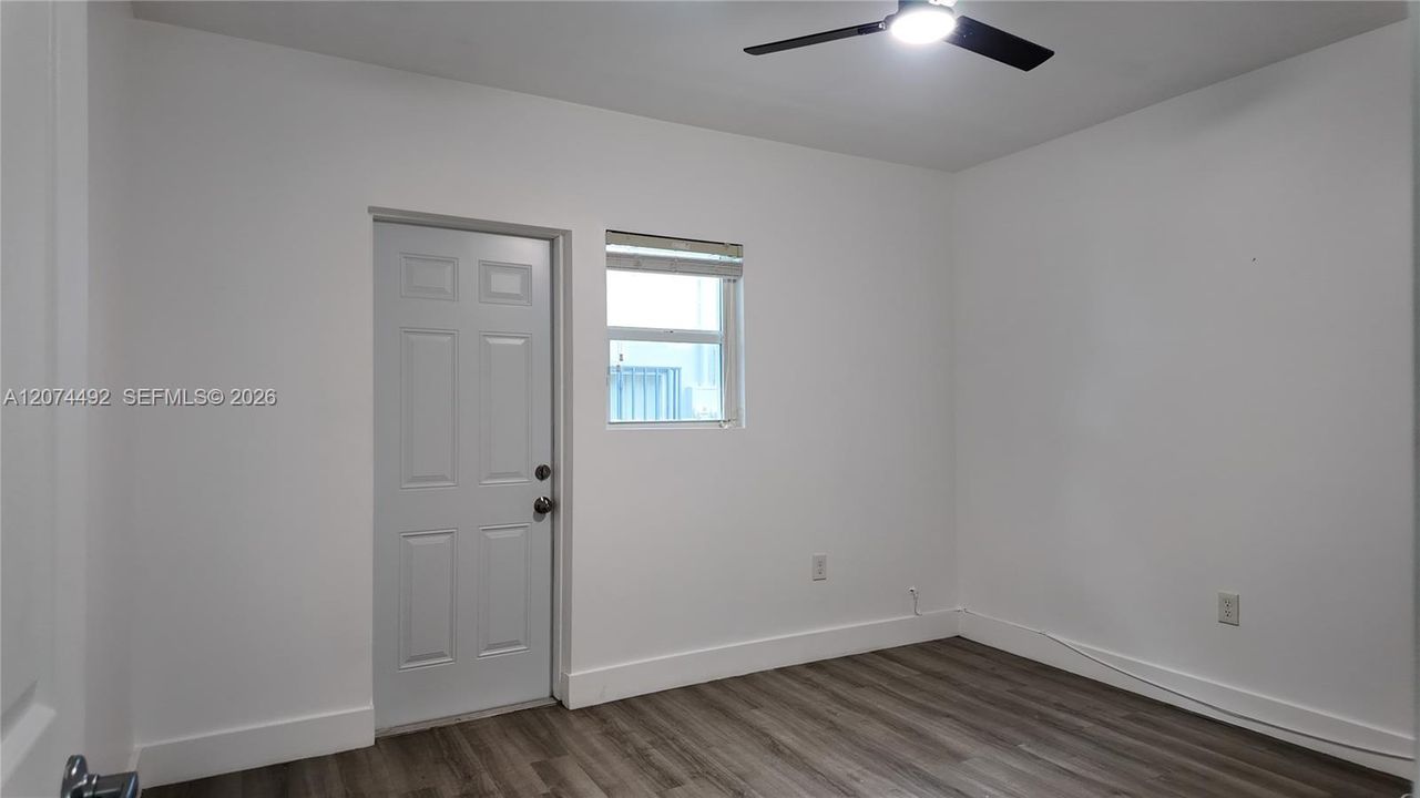 clean, updated room with wood-look flooring, fresh white walls, ceiling fan, and its own exterior access.