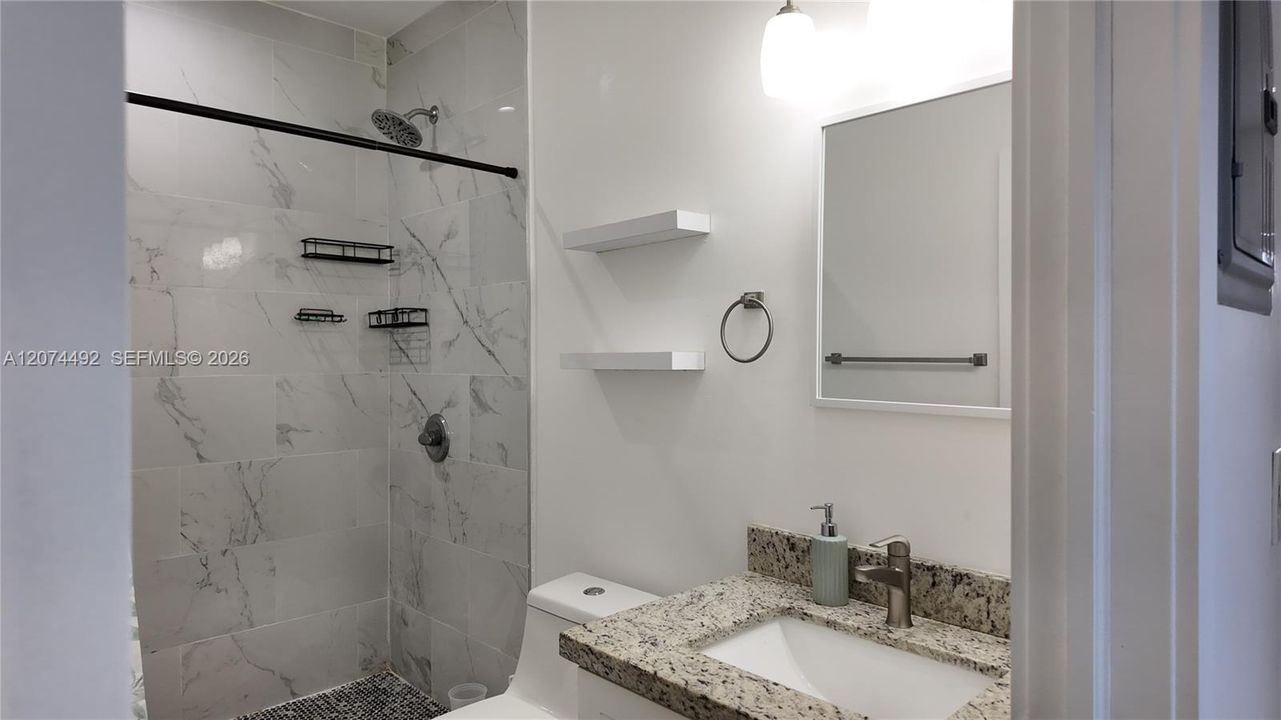 A granite-topped vanity, modern lighting, floating shelves.