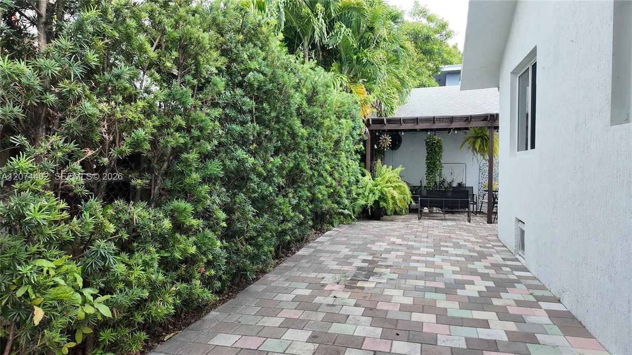 creates a shaded sitting/entertaining area with string lights and greenery.
