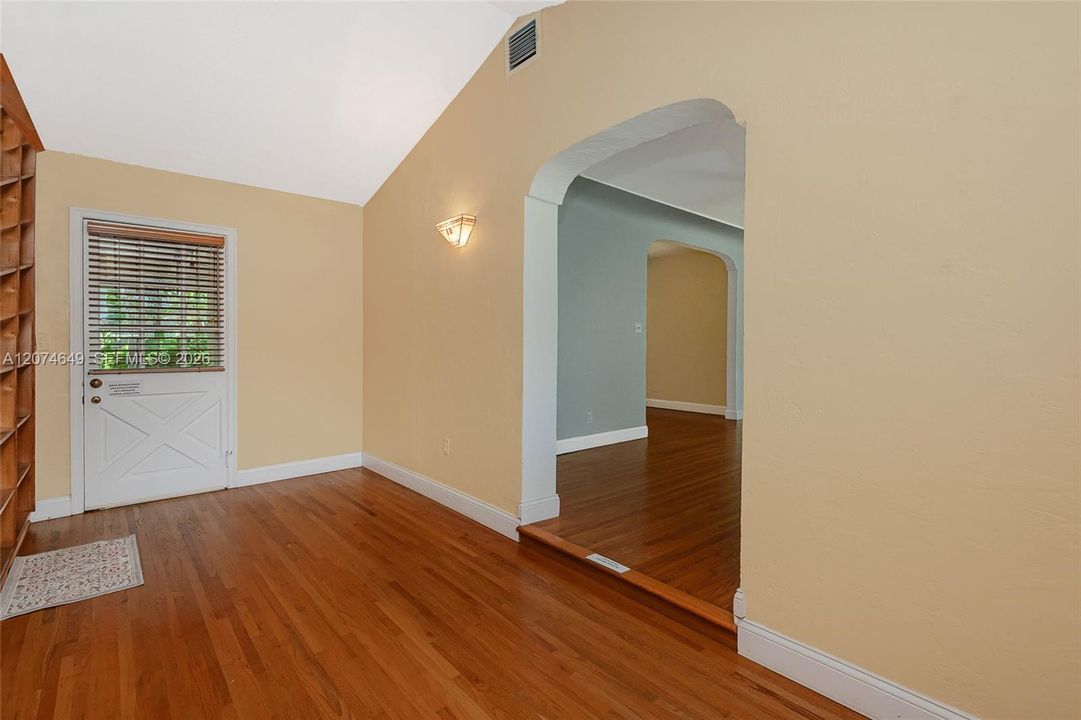 This room is next to the Living room on the right through the opening, and can be used as a Den or Home Office if you need to work from home.  The door is to the outside in the screened-in and roofed patio. This room has an entire wall of shelves on the left.
