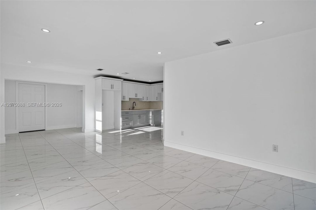 Open floor plan featuring large-format stone-finish tile flooring, recessed lighting, and crisp white walls