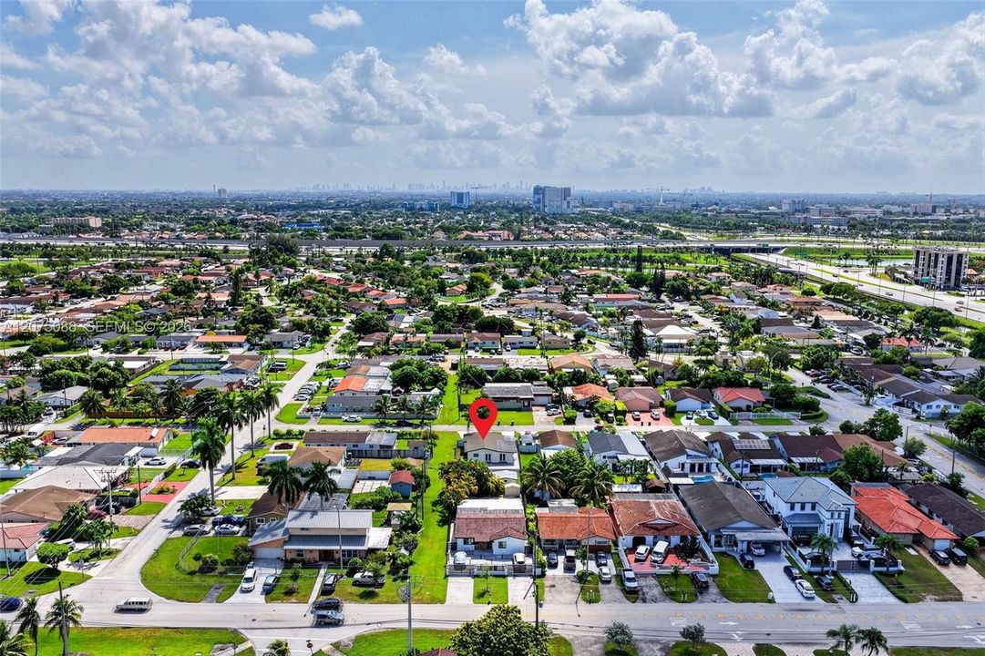 Aerial perspective of a residential property featuring a dedicated driveway, gated front yard, and palm tree landscaping situated within an established suburban neighborhood