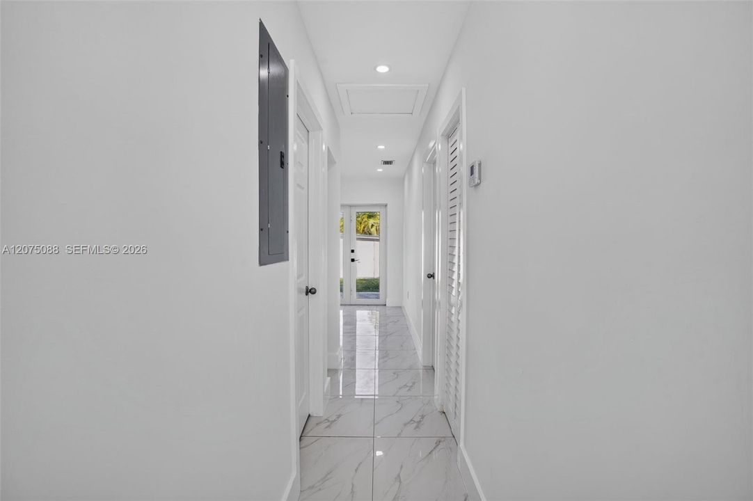 Interior hallway featuring light-toned stone-finish tile flooring, recessed lighting, and dual-panel interior doors
