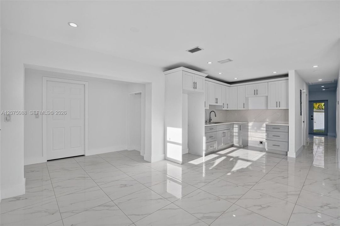 Kitchen featuring white shaker-style cabinetry, stone-finish countertops, tile flooring, recessed lighting, and a gooseneck faucet