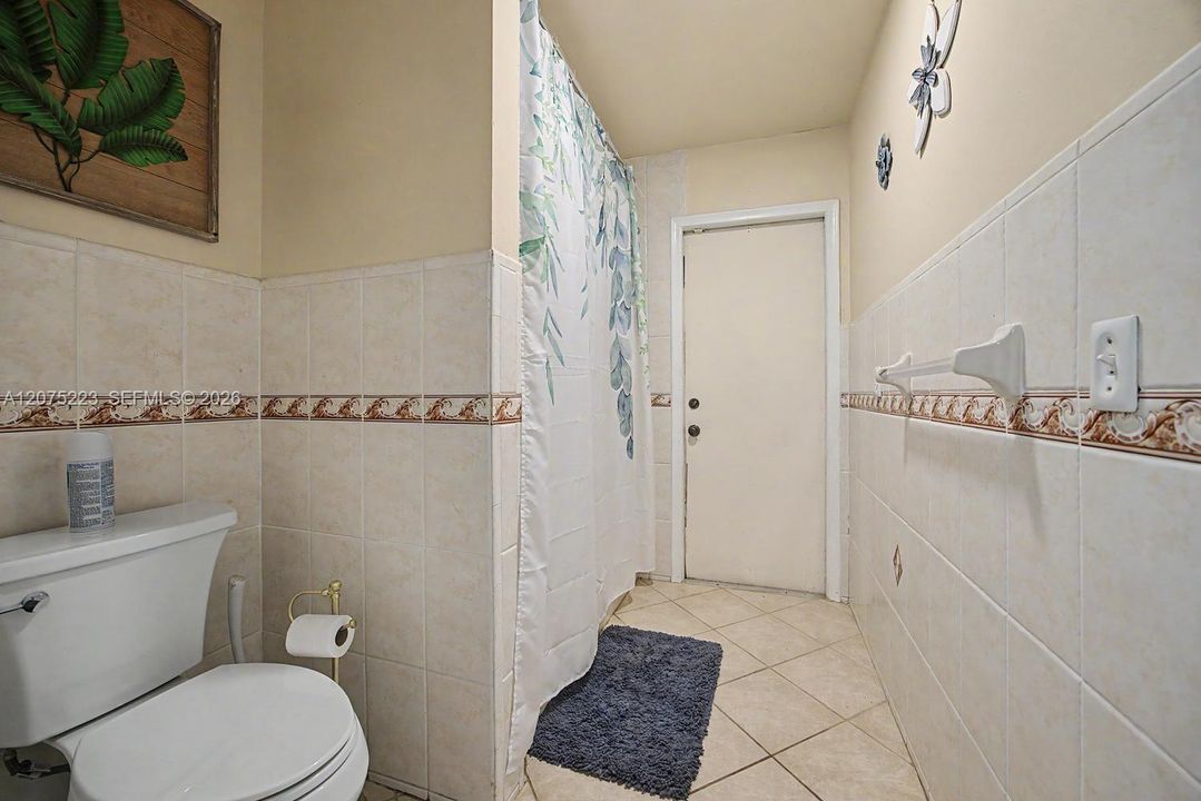 Full bath with direct access to the screened porch, perfectly positioned to serve as a cabana bath for a future pool.