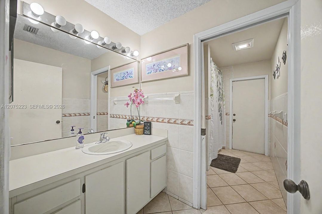Guest bathroom with spacious vanity, tiled walls and tub/shower combination.