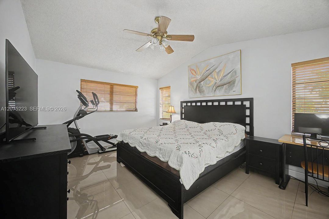 Generously sized primary bedroom with tile flooring, ceiling fan and room for additional furnishings or a sitting area.