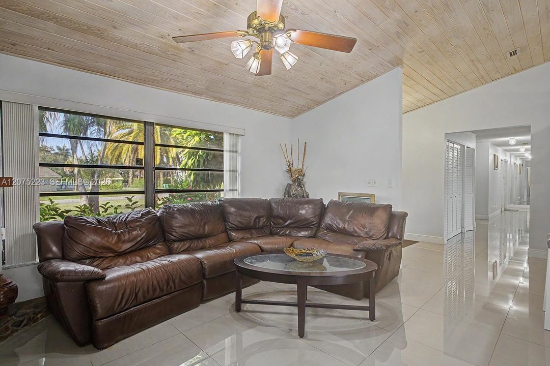 Open-concept living and kitchen area featuring vaulted wood ceilings, tile flooring and abundant natural light.