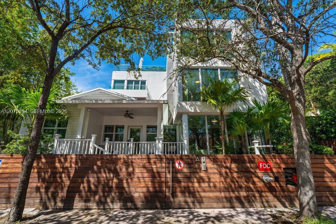 Contemporary façade surrounded by tropical landscaping — boutique Miami Beach townhouse near the ocean and parks.