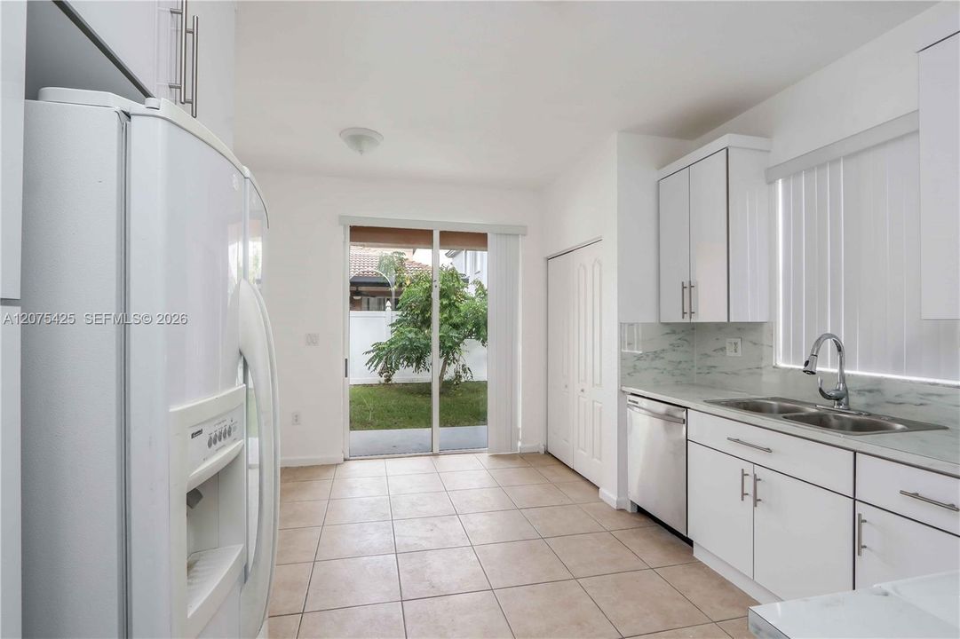 Modern kitchen featuring white cabinetry and appliances.