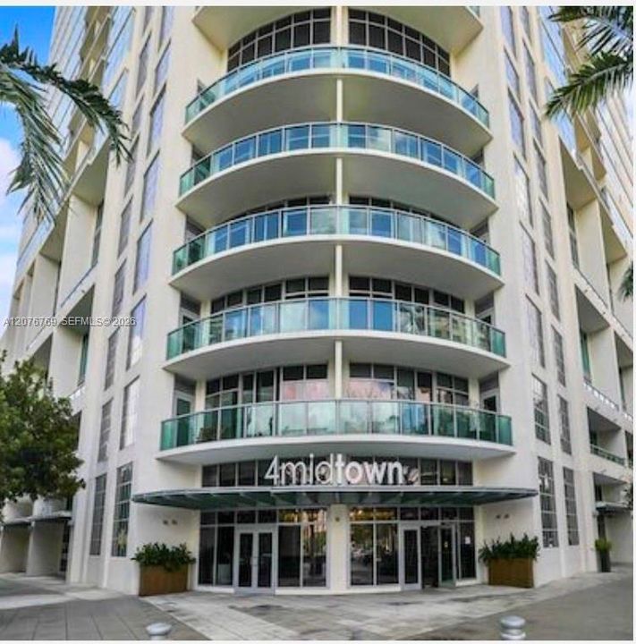Contemporary building façade featuring rounded glass balconies and street level lobby entrance.