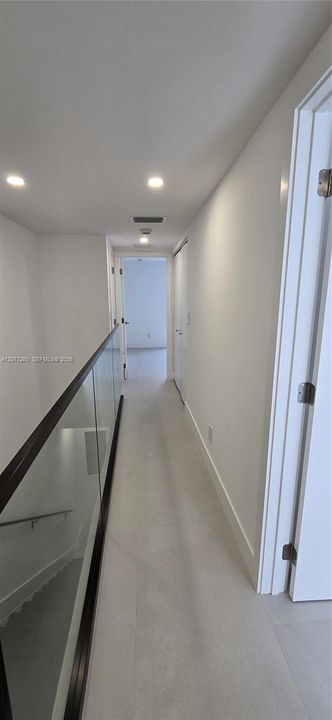 Second floor hall bridges the bedrooms. Contemporary rail and glass.