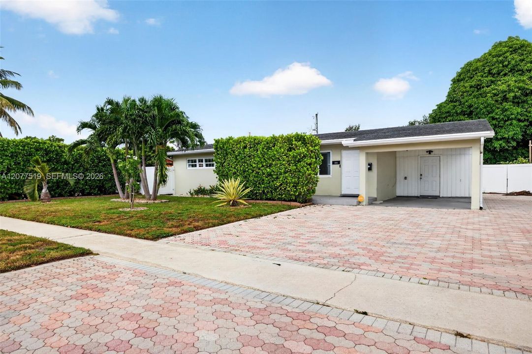 Spacious front yard with mature greenery and a paved driveway leading to the home.