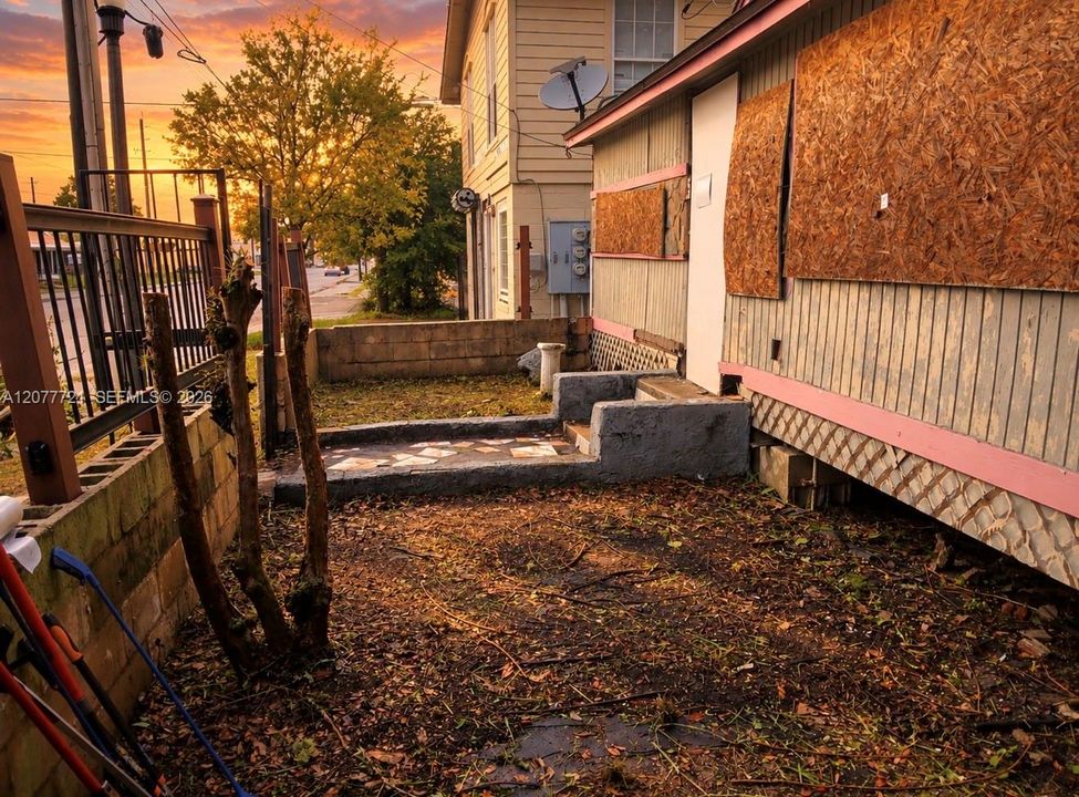 Exterior space featuring concrete block retaining walls, metal fencing, and a stone-tiled concrete landing