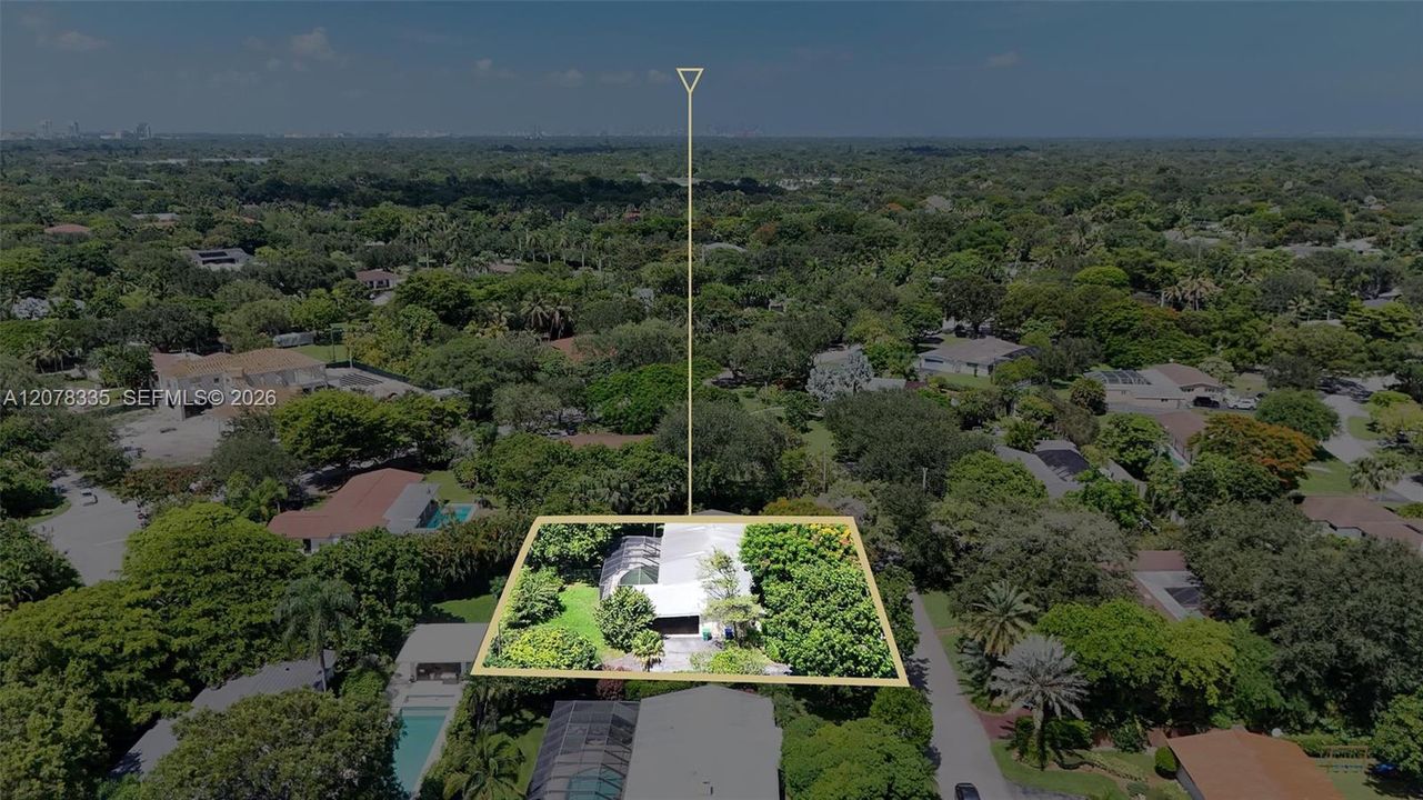 Drone view showcasing the home's layout, spacious lot boundaries, and surrounding lush greenery.