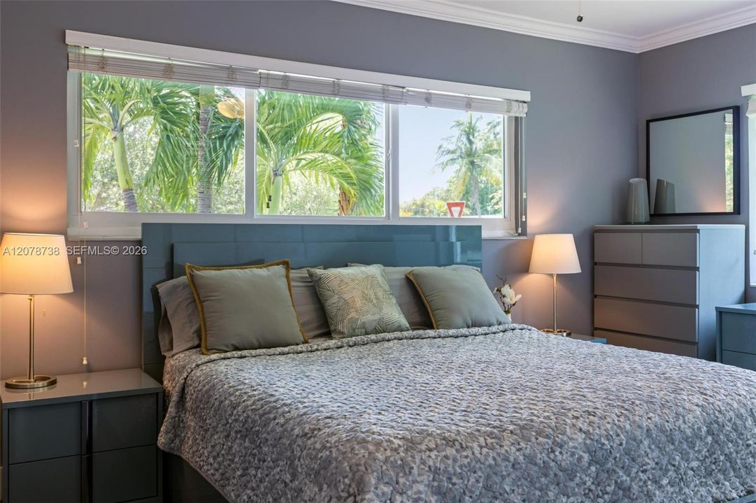 A wall of windows frames tropical greenery, bringing a distinctly Miami backdrop into the bedroom.