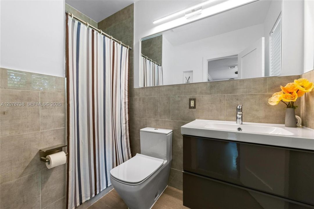 The bathroom continues the home’s contemporary feel with streamlined finishes, a floating vanity, and a neutral palette.