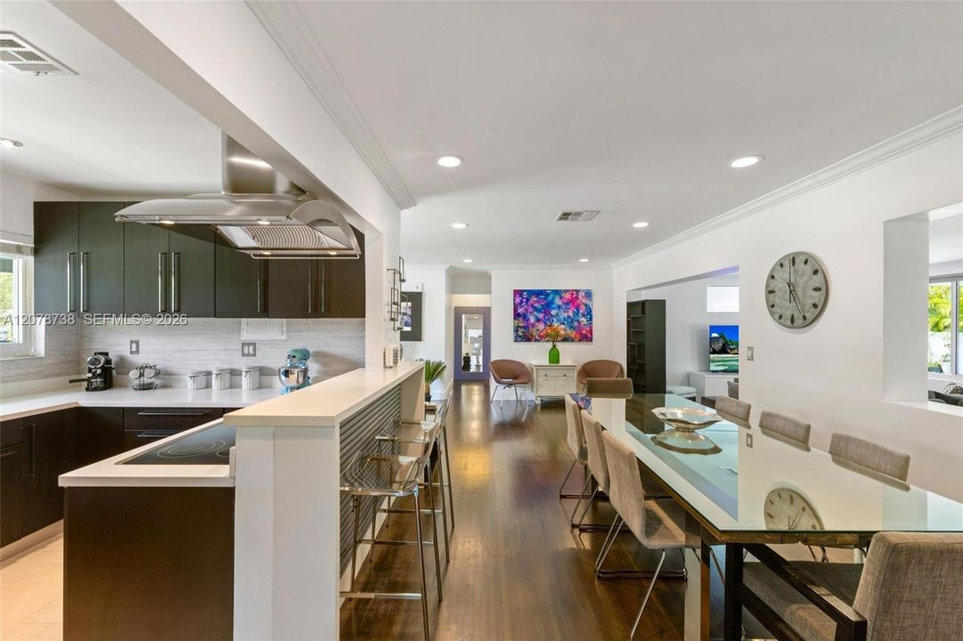 Beyond the main entertaining spaces, the home transitions into a bright secondary living area surrounded by windows and views of the greenery outside.