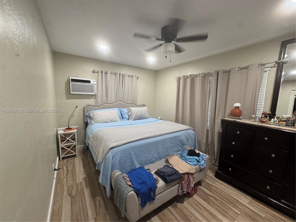 Wood-finish flooring, ceiling fan with integrated lighting, recessed lighting, and wall-mounted air conditioning unit