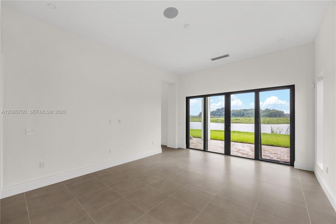 Expansive room featuring large format tile flooring, recessed ceiling lighting, and a multi-panel sliding glass door