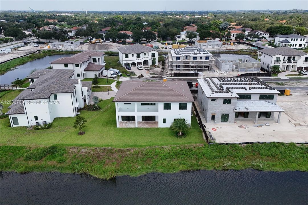 Waterfront property featuring a white stucco exterior and tile roofing