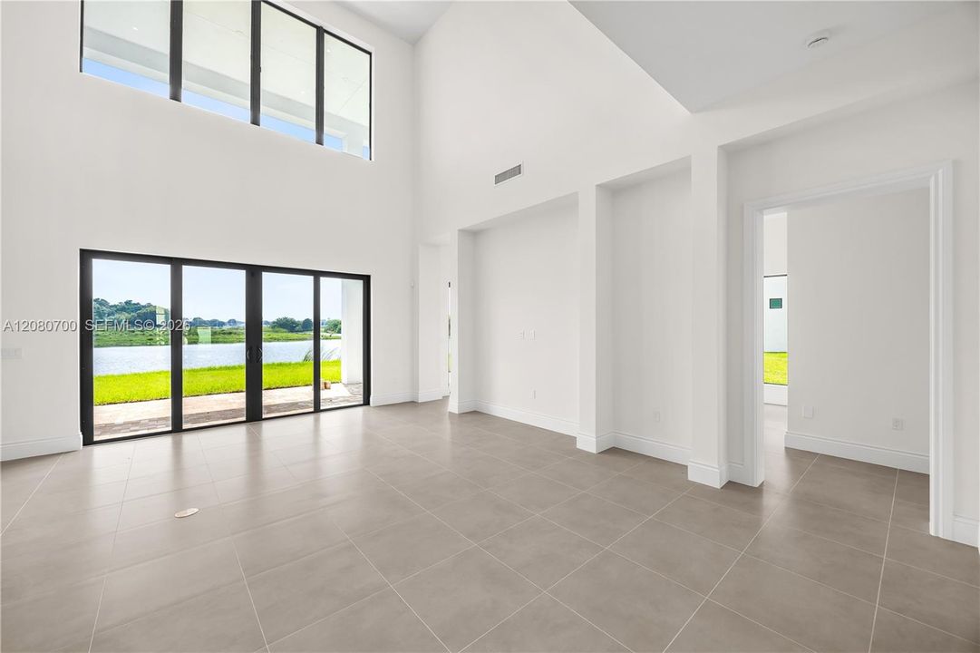 Soaring ceilings with transom windows, large format tile flooring, and a sliding glass door with a water feature backdrop