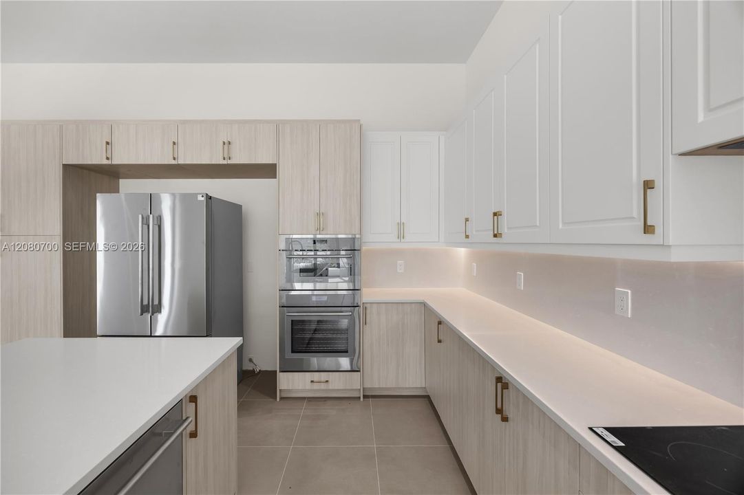 Modern kitchen featuring two-toned cabinetry, stainless steel appliances, and integrated under-cabinet lighting