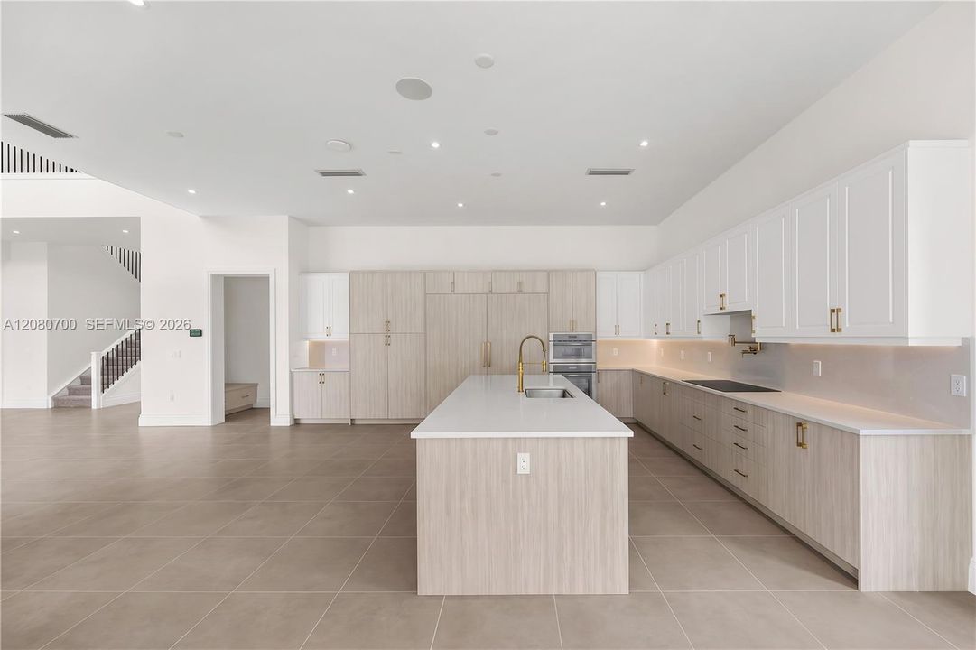 Spacious kitchen featuring an expansive center island, integrated appliances, extensive cabinetry, and tile flooring