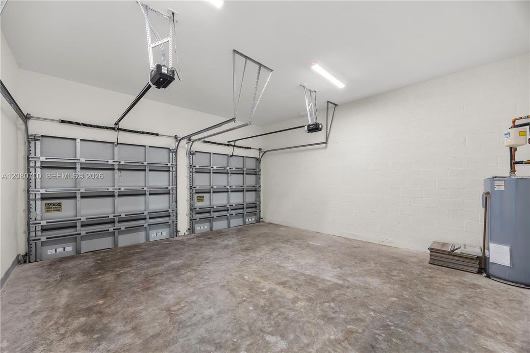 Two garage doors with automatic openers, concrete floor, and fluorescent lighting