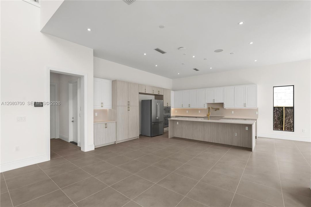 Spacious open-concept kitchen featuring two-tone cabinetry, a large island with countertop, and integrated stainless steel appliances