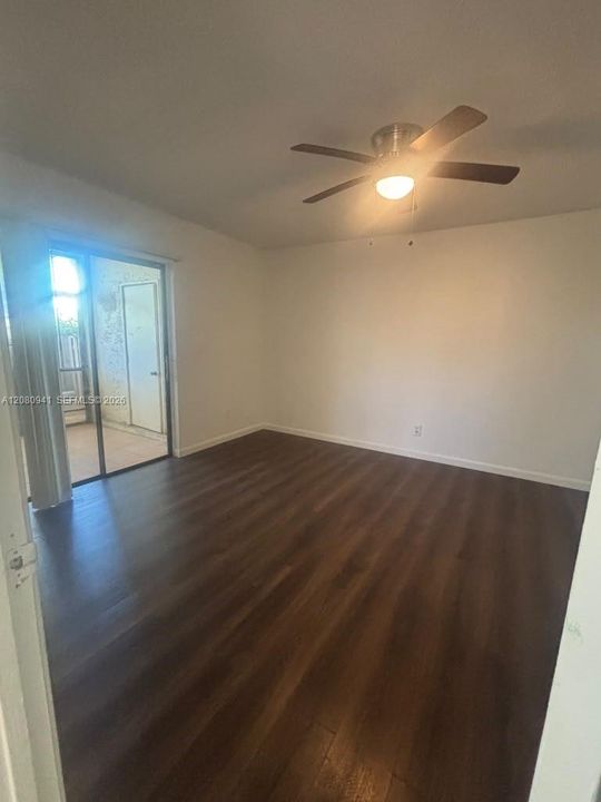 Interior space featuring wood-finish flooring, a ceiling fan with integrated lighting, and a sliding glass door providing external access