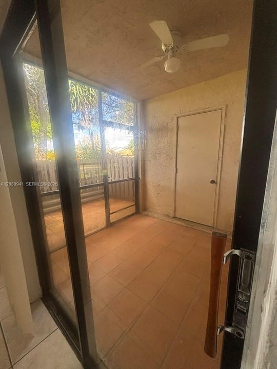 Enclosed patio featuring tile flooring, full-height screen panels, a ceiling fan, and a solid-core entry door