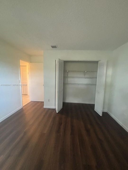 Room featuring wood-finish flooring, a closet with bi-fold louvered doors, and built-in shelving