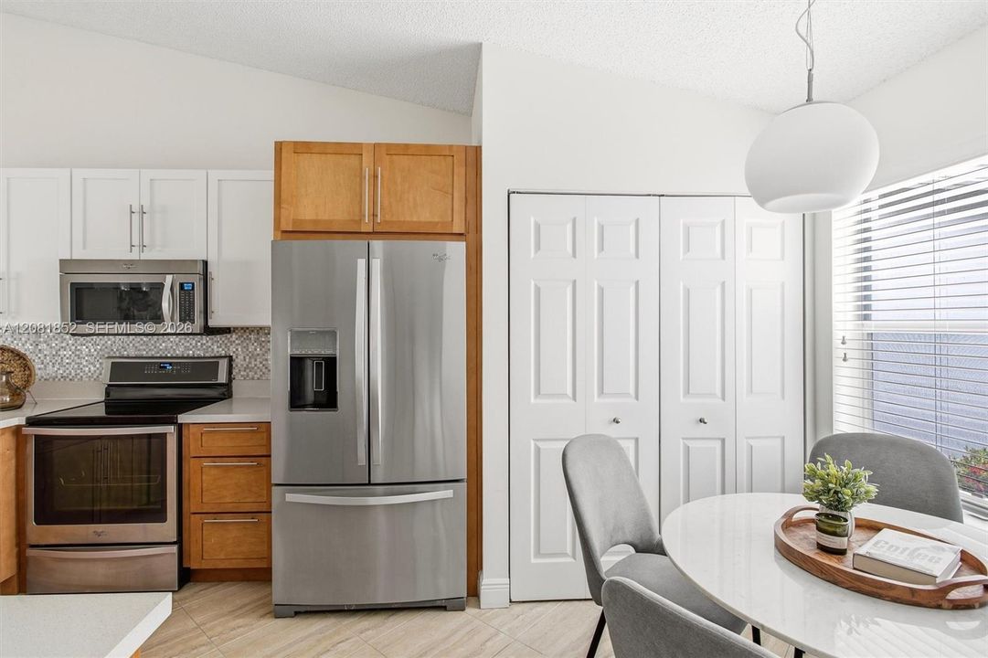 Warm wood cabinetry pairs beautifully with sleek countertops in this eat-in kitchen.