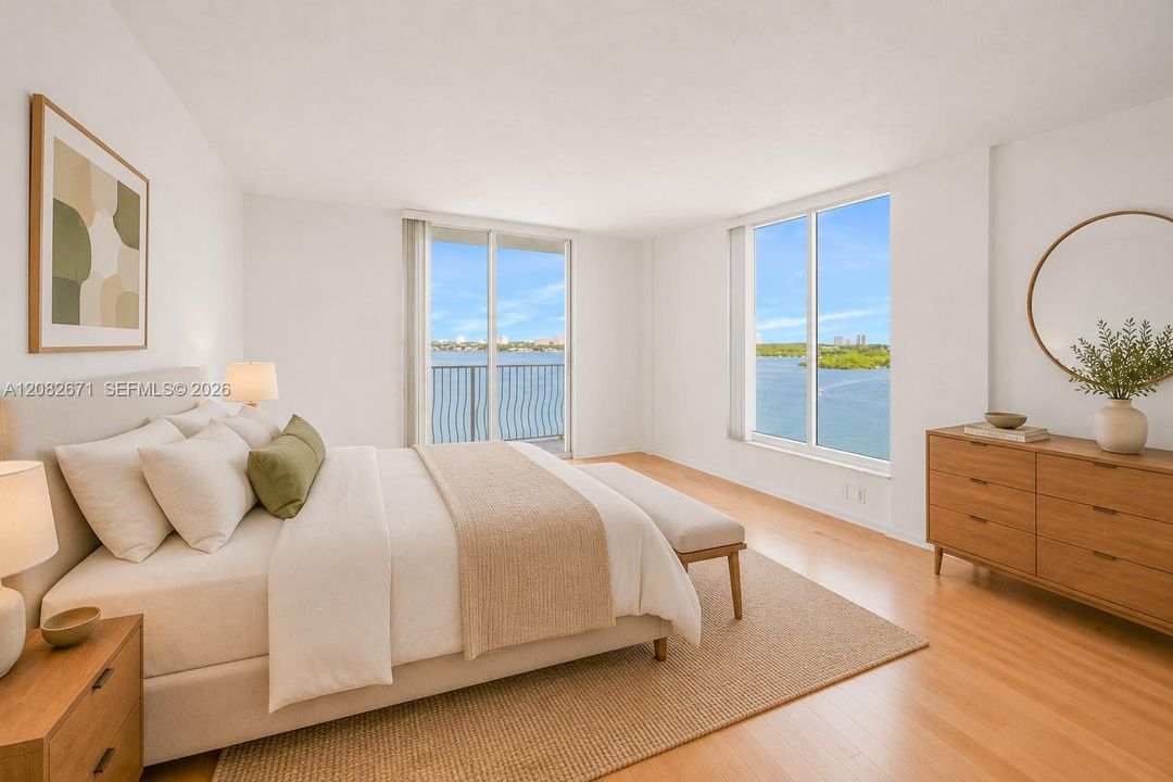 Primary suite, digitally staged, with direct bay views and mirrored closet wall.