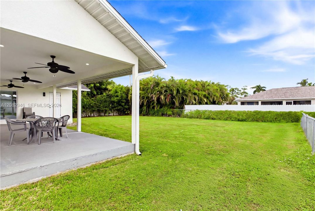 Multiple ceiling fans enhance the covered outdoor area while overlooking the spacious yard & tropical Florida setting.