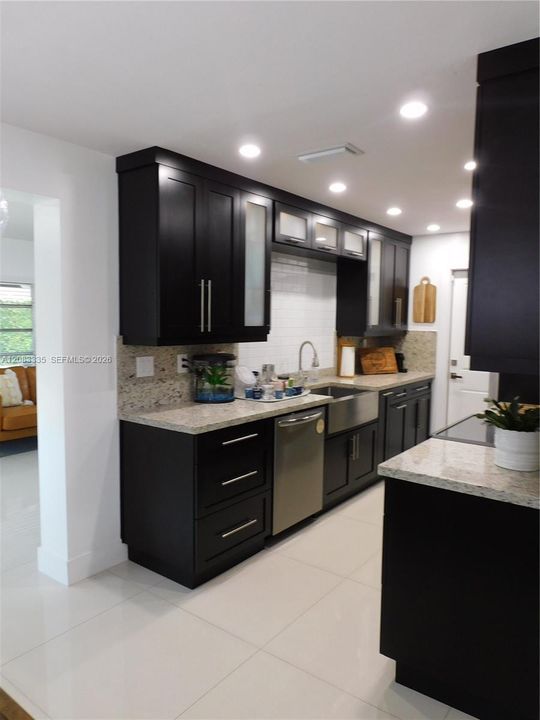 Updated Kitchen with Upgraded Cabinetry, Granite Countertops & Backsplash, and Stainless Steel Appliances. High hats provide a nice ambiance.