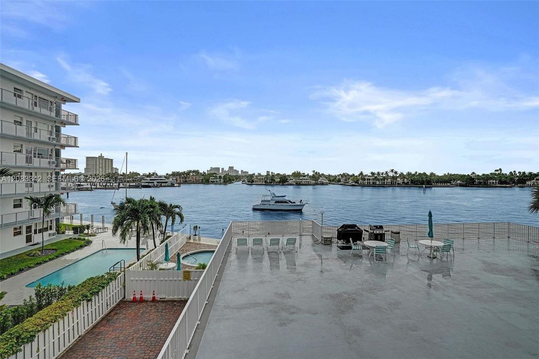 View from balcony of Deck, chairs, table & with grill above the pool