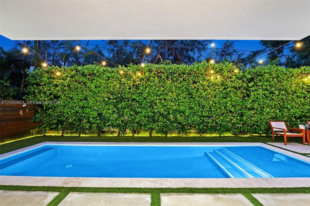 Modern, salt-water lap pool with twinkling lights in private yard.