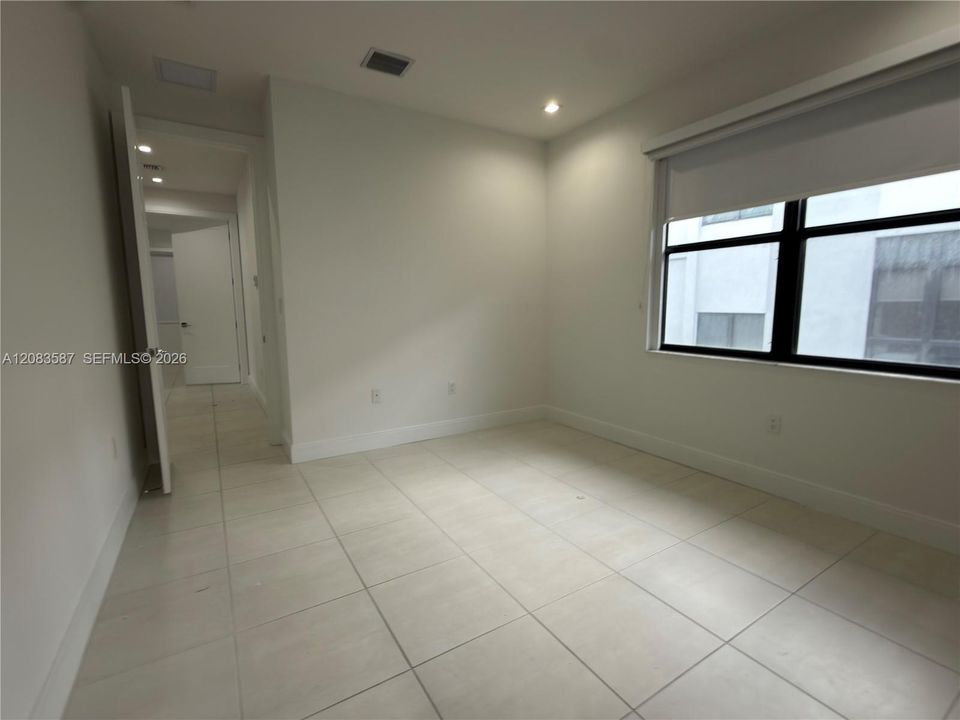 Large-format neutral tile flooring, recessed lighting, and expansive window with black frame finish