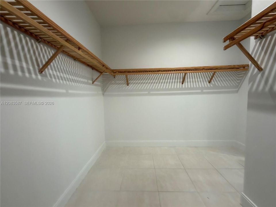 Walk-in storage space featuring large-format ceramic floor tiles and wrap-around wood-slat shelving