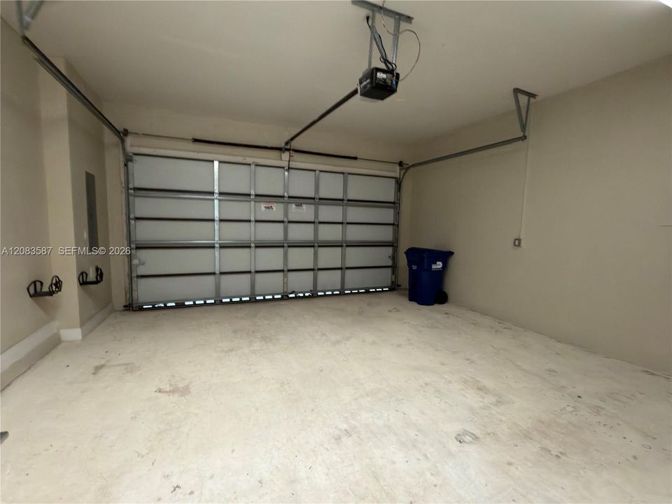 Attached garage featuring an automatic opener, concrete flooring, and interior wall-mounted electrical panel